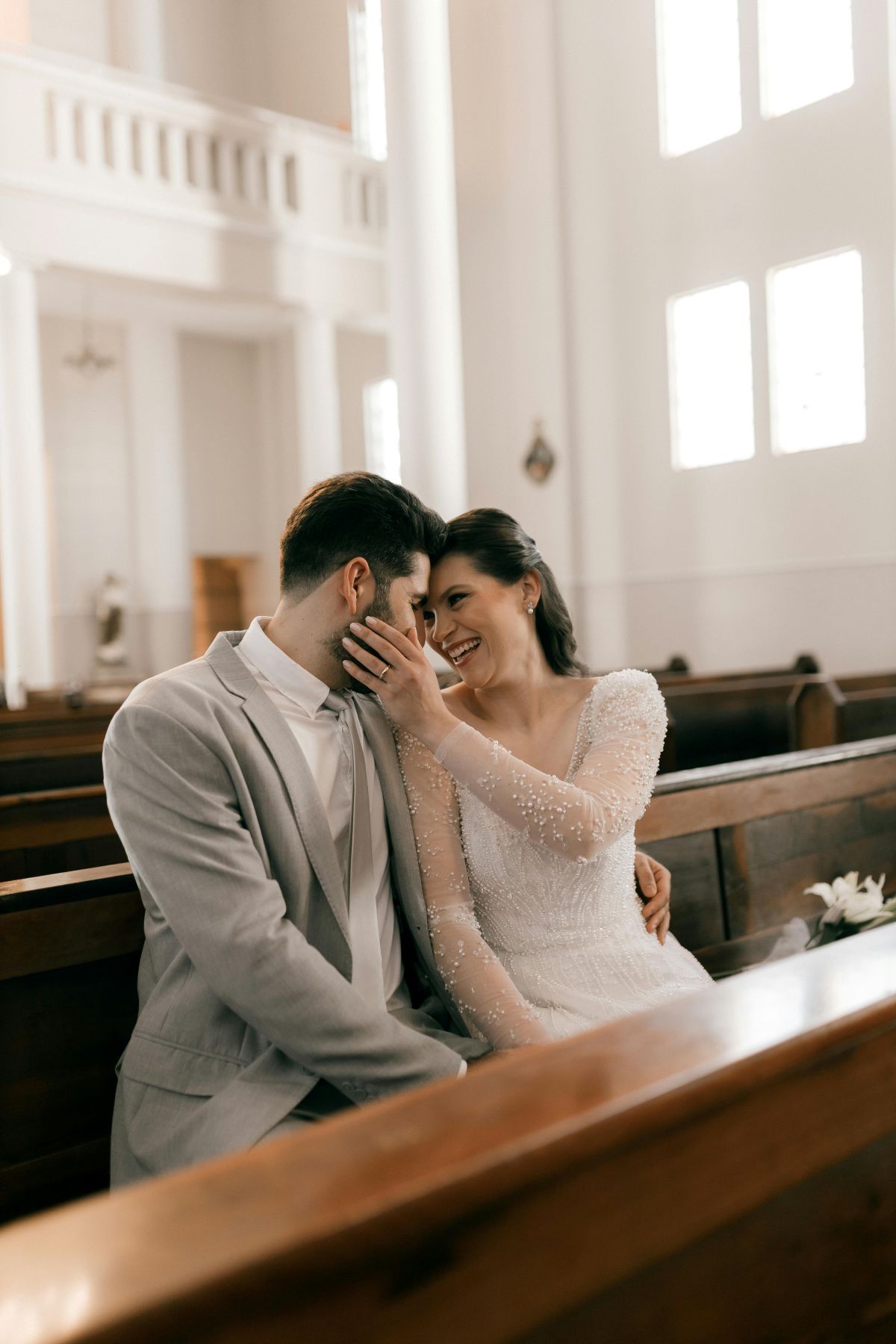 Couple homme et femme fraîchement marié assis sur un banc d’église, souriant, les visages collés