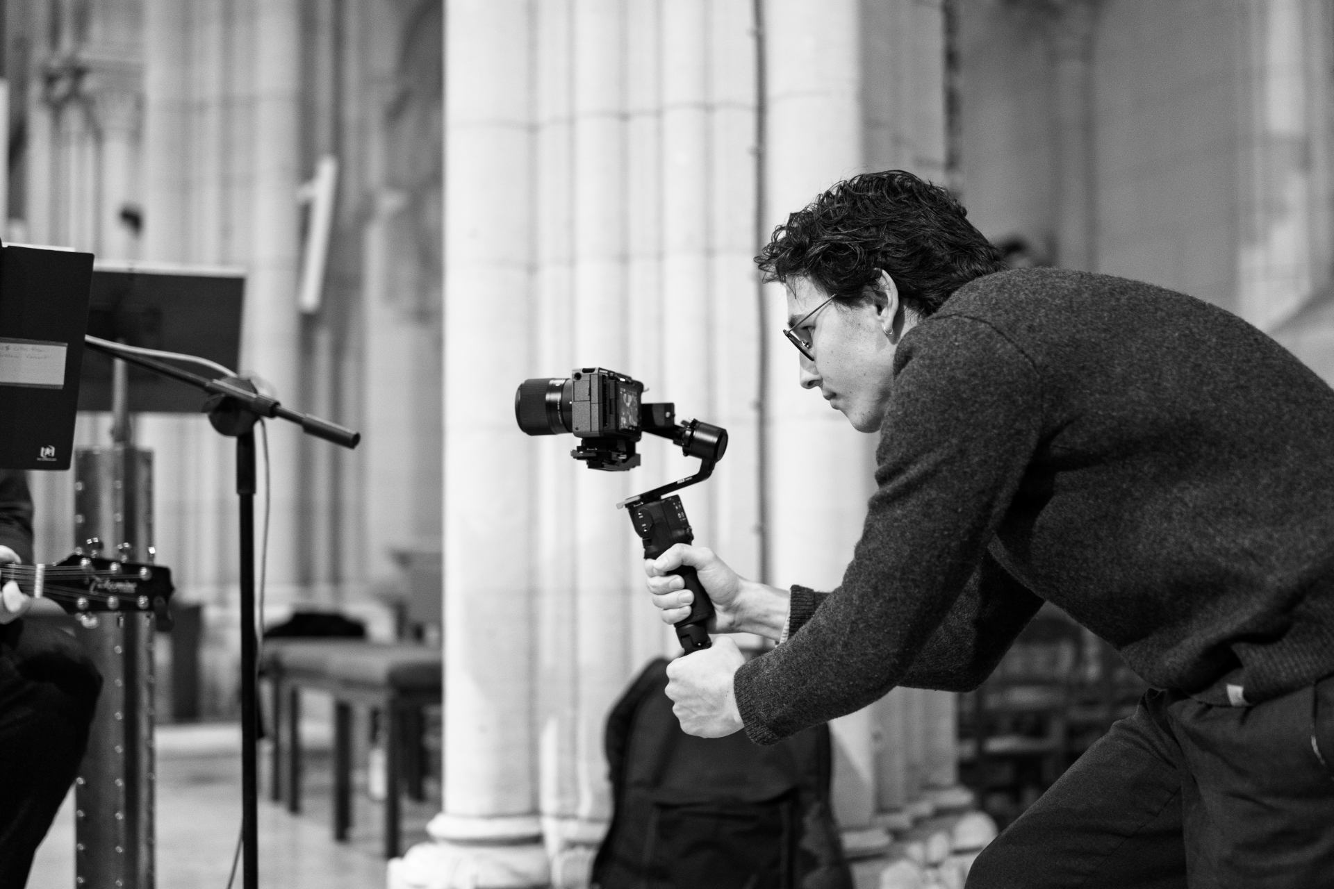 Vidéaste filmant un concert dans une église avec une Sony FX30, photographie en noir et blanc prise de profil